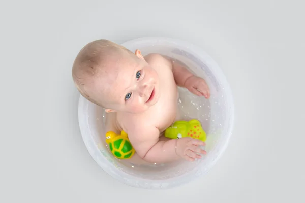 Lindo bebé teniendo un baño en cubo transparente y jugando con t — Foto de Stock