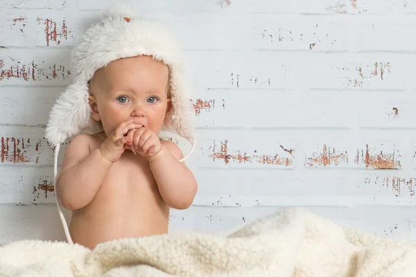 Baby girl in a cap enjoying warmth of the room — Stock Photo, Image