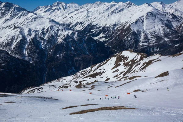 许多滑雪者在阳光灿烂的冬日乘坐阿尔卑斯山.冬季风景-滑雪场全景,有滑雪场.阿尔卑斯山。奥地利. — 图库照片