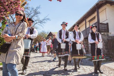 HOLLOKO, HUNGARY - 12 Nisan 2019 Paskalya Festivali Macaristan 'ın Holloko kasabasında. Erkekler kızların üzerine su serper.