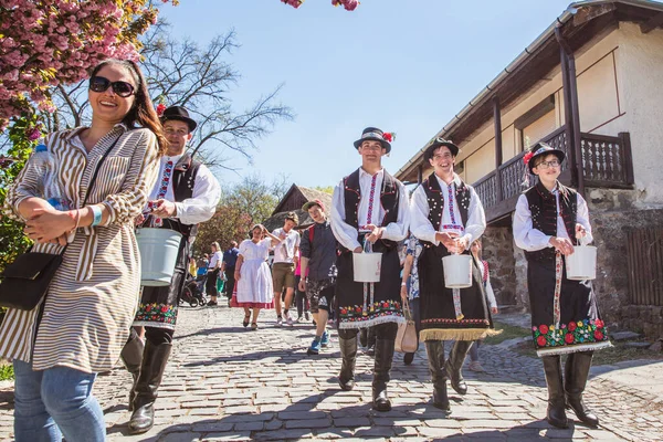 HOLLOKO, HUNGARY - 12 Nisan 2019 Paskalya Festivali Macaristan 'ın Holloko kasabasında. Erkekler kızların üzerine su serper.