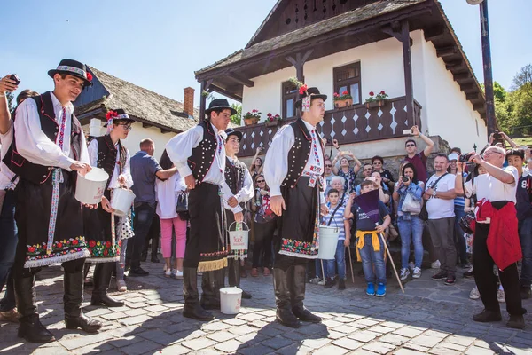 HOLLOKO, MAGYARORSZÁG - 2019. április 12.Húsvéti fesztivál a magyarországi Holloko folklórfaluban. A fiúk vizet locsolnak a lányokra. — Stock Fotó