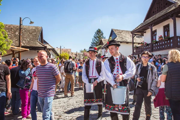 HOLLOKO, MAGYARORSZÁG - 2019. április 12.Húsvéti fesztivál a magyarországi Holloko folklórfaluban. A fiúk vizet locsolnak a lányokra. — Stock Fotó