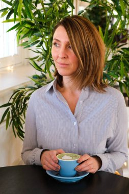 Kafede çay yudumlayan genç bir kadın.