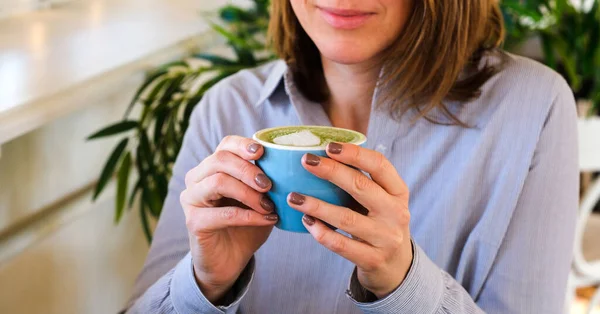 Jovem mulher no café tomando chá matcha de uma xícara — Fotografia de Stock