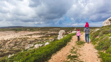 Baba ve iki kızı deniz boyunca yol boyunca yürürler. Deniz kenarında güzel bir vadi. Kıbrıs Rum Kesimi 'nde Deniz Burnu Ayia Napa