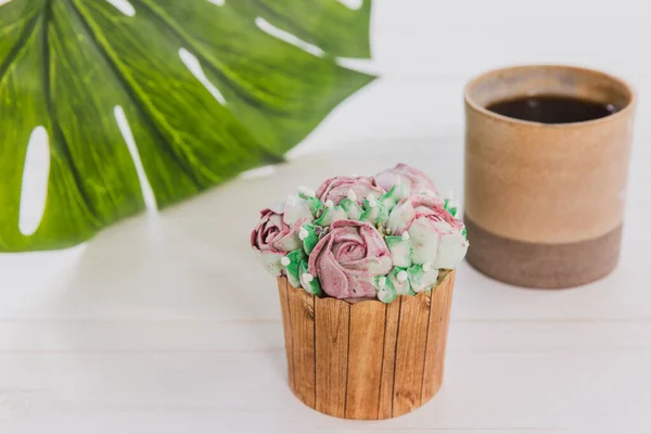 Süti vajvirág fehér fa asztalon csésze forró ital és zöld levél a háttérben — Stock Fotó