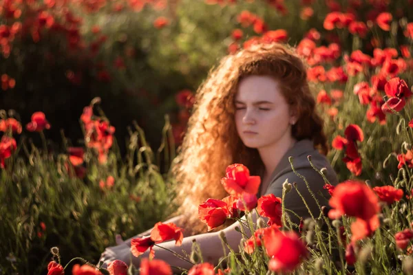 Selektive Fokusaufnahme in rotem Mohnfeld mit jungem schönen roten Gesicht auf Hintergrund — Stockfoto