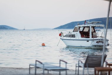 Güzel turkuaz mavi denizde Hırvat bayraklı beyaz bir yat sahilin yanında duruyor.