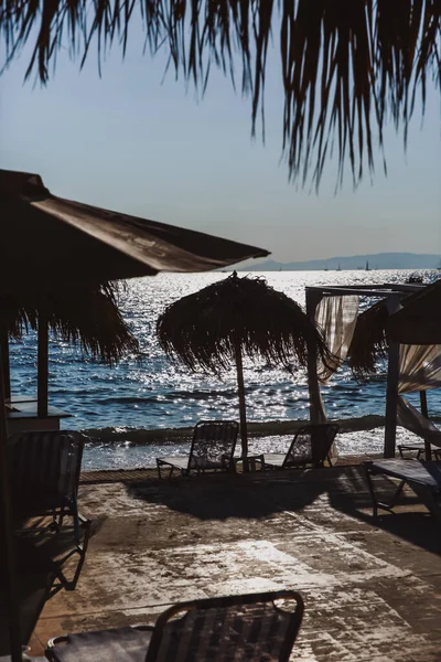 Vue sur la plage avec chaises longues et parasols en bois. Coucher de soleil en mer. — Photo