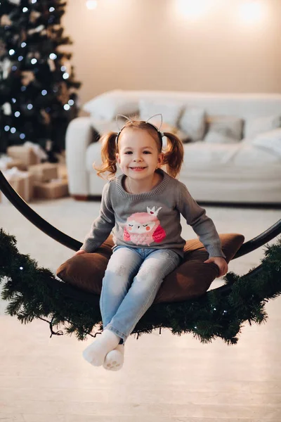 Adorable niñita en el columpio de Navidad. Árbol de Navidad. — Foto de Stock