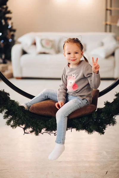 Niño bonito sentado en el columpio de Navidad. Árbol de Navidad. — Foto de Stock