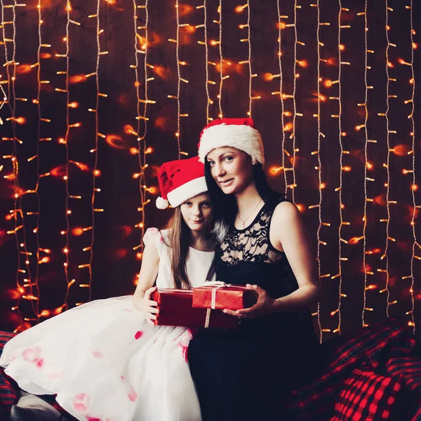 산타클로스 모자를 쓴 어머니와 딸, 조명용 화랑에 반대하는 모습. — 스톡 사진