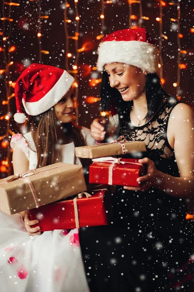 Noel hediyeli anne ve kız. Parlak ışıklı çelenklere karşı Noel hediyeleri.. — Stok fotoğraf