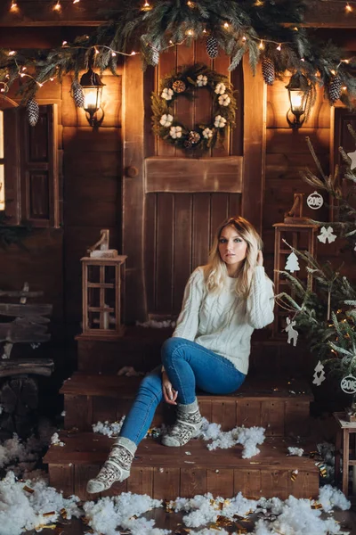 어느 아름다운 소녀가 신해를 위해 장식 한마을 집의 아늑 한 마당에 앉아 있다. — 스톡 사진