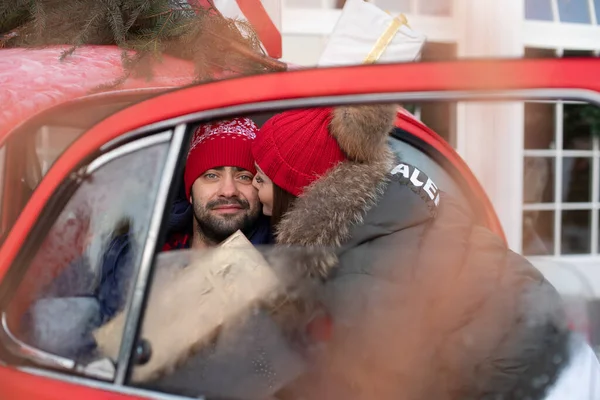 Joven pareja encantadora compra regalos de Navidad para su familia y los lleva a casa en un coche rojo — Foto de Stock