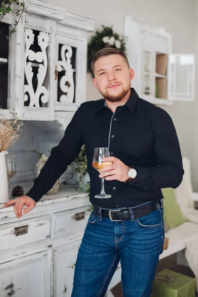 Hermoso hombre en una camisa y pantalones con una copa de champán celebra el nuevo año — Foto de Stock