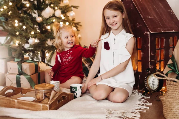 漂亮的小女孩斯迪丝波浪形的头发和一个装有礼物的盒子坐在一起，她和姐姐欢天喜地 — 图库照片