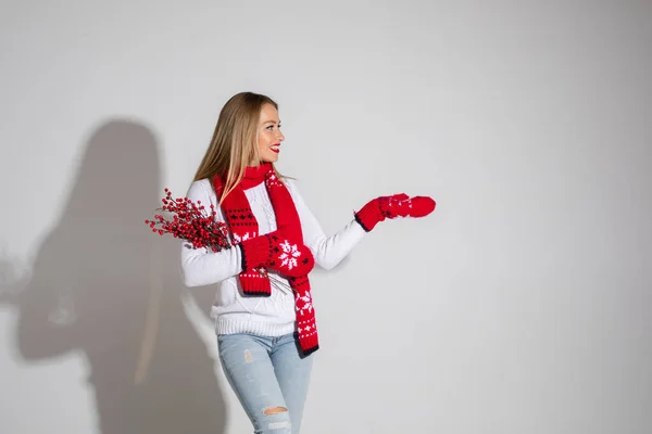 Mujer atractiva en suéter blanco, bufanda roja y mitones rojos con diseño de Navidad muestra algo — Foto de Stock