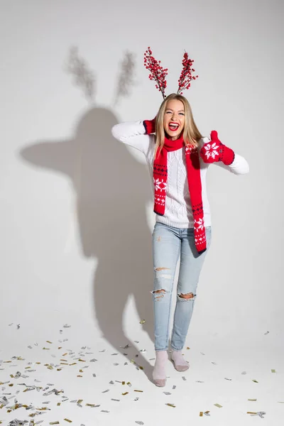 Mujer atractiva en suéter blanco, bufanda roja y mitones rojos con diseño de Navidad se regocija y como algo — Foto de Stock