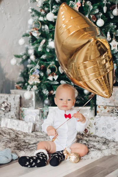 Kleine schattige jongen zit met een gouden ballon — Stockfoto