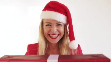 Noel Baba şapkası takan ve Noel hediyesini stüdyoda tutan güzel bir bayan.