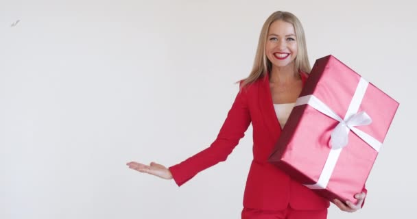 Gyönyörű nő piros ruhában karácsonyi ajándékkal. — Stock videók