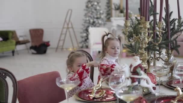 두 어린 소녀가 탁자에 앉아 금사 슬을 들고 있다 — 비디오