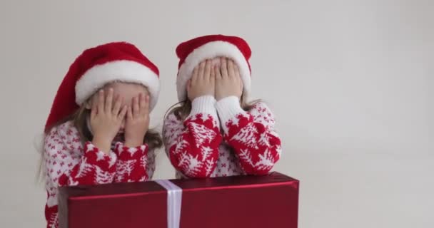Flickor i Santa hattar gömmer sig och öppnar ögonen. — Stockvideo