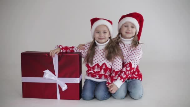 Vackra systrar sitter nära den stora röda lådan med julklapp tillsammans — Stockvideo