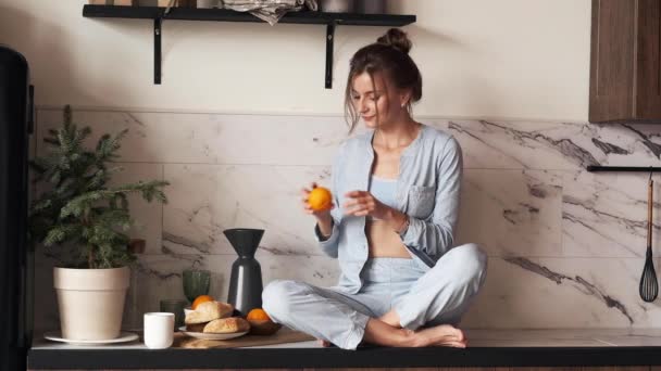 Mulher desfrutando de cheiro de laranja na cozinha. — Vídeo de Stock