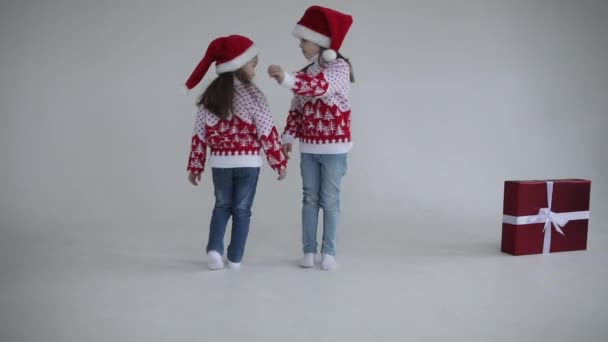 Dos hermanas lindas en sombreros de Santa dando vueltas a su alrededor — Vídeo de stock