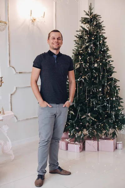 Caballero alegre sonriendo y de pie cerca del árbol de Navidad — Foto de Stock