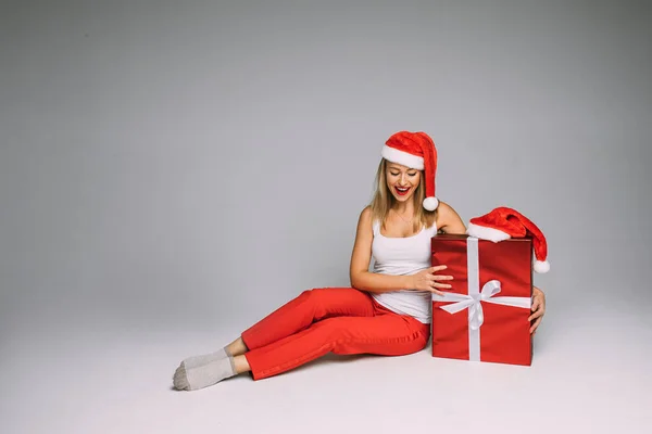 Jolie femme dans le chapeau de Père Noël posant avec boîte cadeau de Noël — Photo