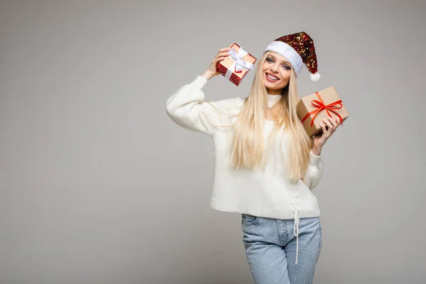 Mujer divertida con sombrero de Navidad se sienta con una gran caja roja y pensar lo que está dentro, imagen aislada sobre fondo blanco — Foto de Stock