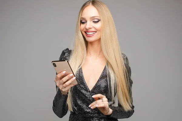 Bella giovane donna sms con i suoi amici con il telefono e sorride — Foto Stock