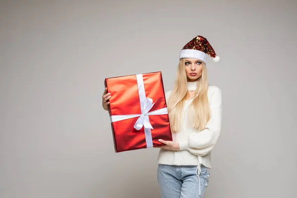 Όμορφη λυπημένη κοπέλα κρατά μεγάλο χριστουγεννιάτικο δώρο της, εικόνα απομονωμένη σε λευκό φόντο — Φωτογραφία Αρχείου