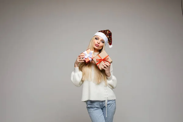 Bonita mujer caucásica sostiene dos pequeños regalos y sonrisas aisladas sobre fondo blanco — Foto de Stock