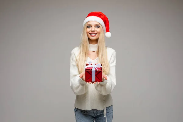 Bonita mujer caucásica sostiene una pequeña caja roja con un regalo y posa para la cámara aislada sobre fondo blanco — Foto de Stock