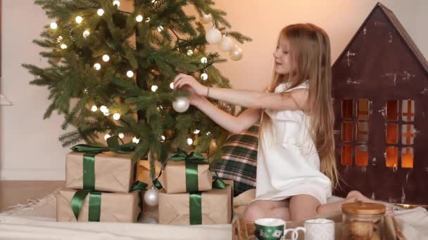 Улыбающаяся красивая маленькая девочка с новогодними подарками дома — стоковое видео