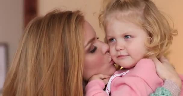 Genç güzel anne kızını yanağından öpüyor. — Stok video