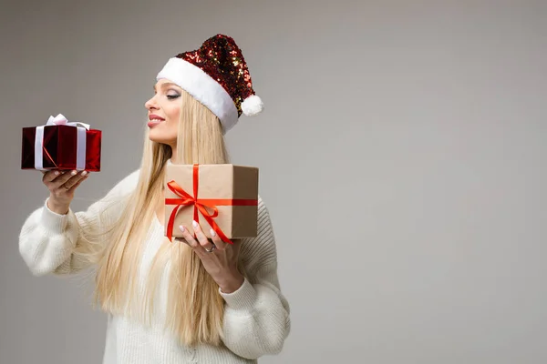 Chica rubia en brillante sombrero de Santa con dos regalos. — Foto de Stock