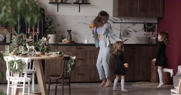 Dançando jovem mãe, filhas se divertindo feriados festivos juntos em Xmas cozinha decorada. Conceito de maternidade feliz — Vídeo de Stock