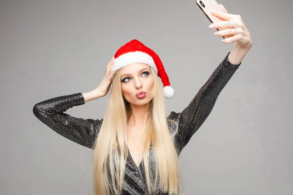 Portrait de jolie jeune femme aux cheveux longs sourit et tient un téléphone portable dans ses mains prend des photos de son joli visage et pose pour l'appareil photo — Photo