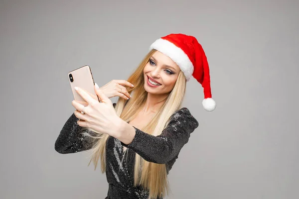 Portrait de jolie jeune femme aux cheveux longs sourit et tient un téléphone portable dans ses mains prend des photos de son joli visage — Photo