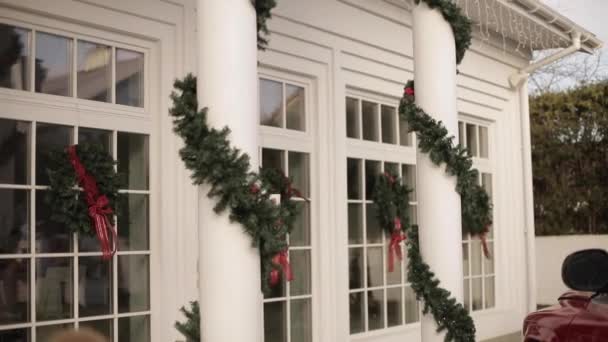 Caminante en ropa de invierno con taza de té caliente cerca de la casa decorada para Navidad, fin de semana de invierno festivo — Vídeo de stock