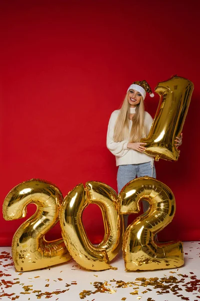Attrayant femme en vêtements confortables sourit près de grands ballons d'or avec des chiffres 2021 — Photo