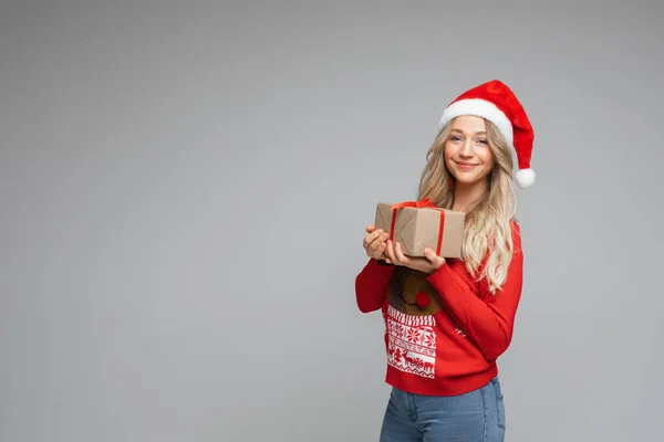 Retrato de mujer en suéter y sombrero de cristmas sostiene una caja con un regalo — Foto de Stock