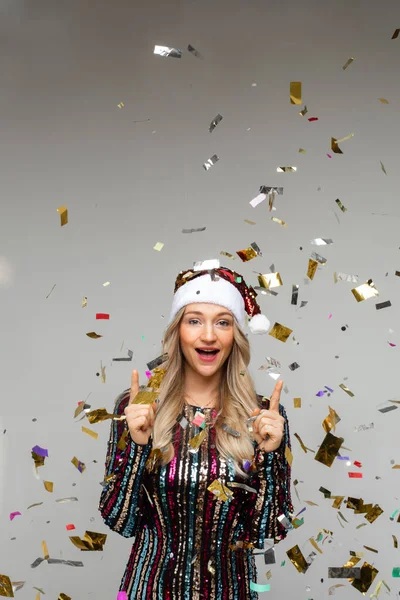 Femme gaie en robe et chapeau de Noël se réjouit avec beaucoup de confettis autour d'elle — Photo