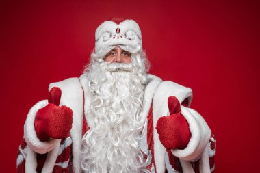 Noel Baba, kırmızı stüdyo arka planında, festival için fotokopi alanı olan bir jesti onayladı.